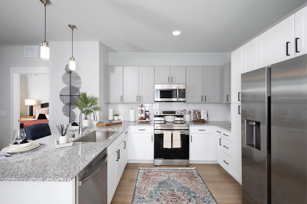 a kitchen with stainless steel appliances and granite countertops at a senior apartment community