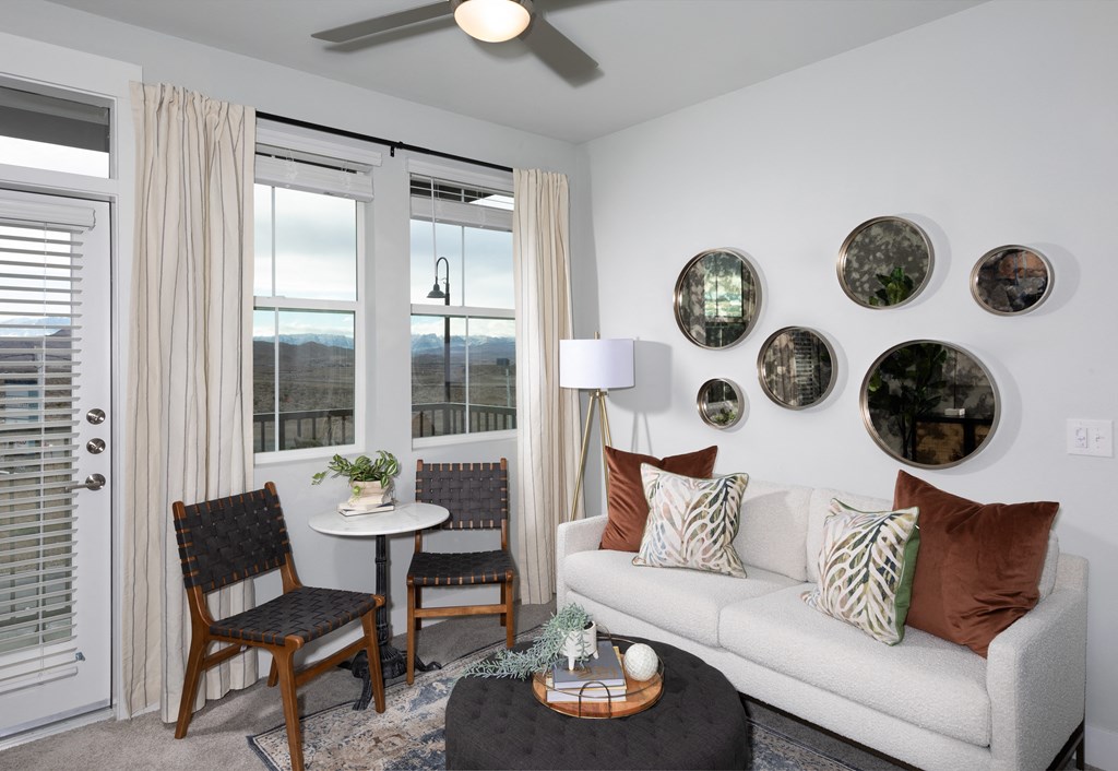 a living room with a ceiling fan and windows at a senior apartment community