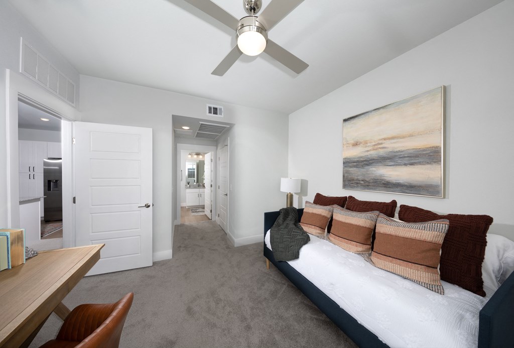 a bedroom with a daybed, ceiling fan, and desk at a senior apartment community