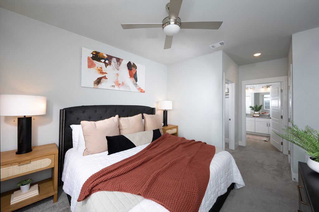 a bedroom with a queen-sized bed and ceiling fan at a senior apartment community