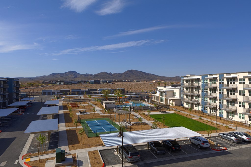 an aerial view of a pickleball court, lawn and resort-style pool at a senior apartment community
