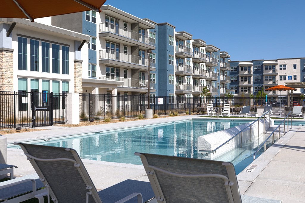 a resort-style pool and lounge chairs at a senior apartment community