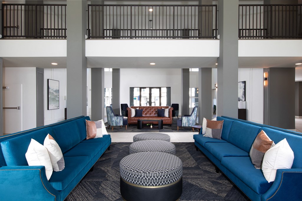 a lobby with blue couches and pillows and a table and chairs