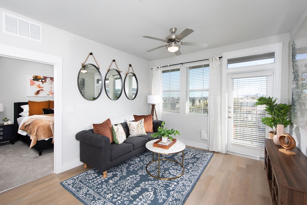 a living room with a ceiling fan and door that opens to a patio at a senior apartment community
