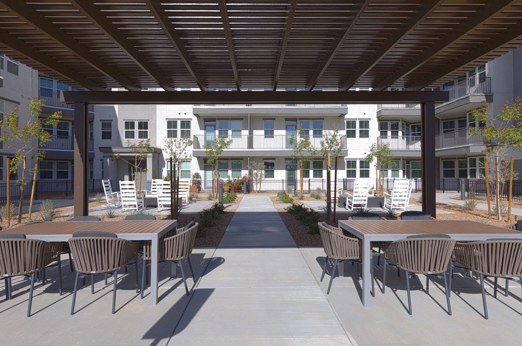 a patio area with tables and chairs and a building in the background