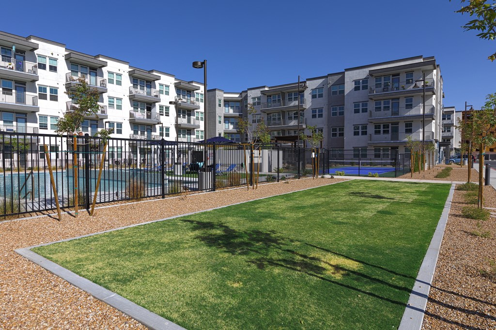 a large green lawn in front of an apartment building with a pool