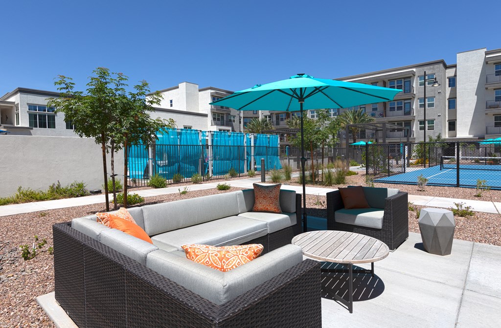 a patio with couches and chairs and a table with an umbrella