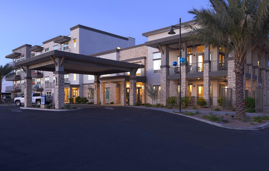 the facade of a hotel with palm trees at dusk