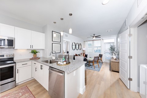 an open kitchen and living room with white cabinets and stainless steel appliances