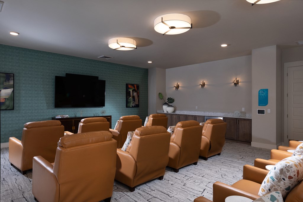 a theater room with brown leather chairs and a wall mounted tv