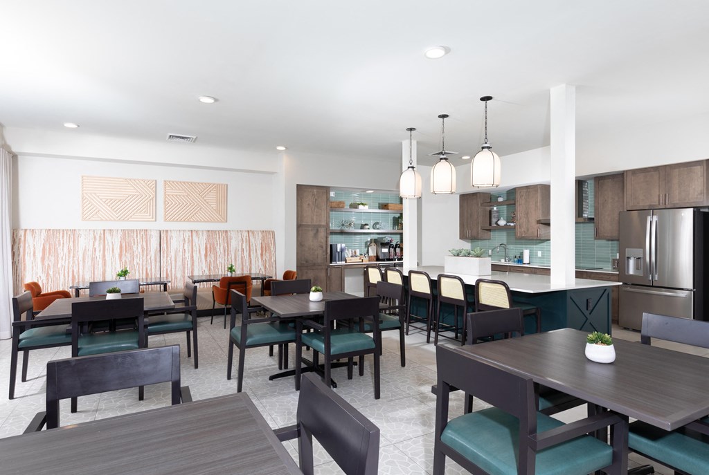a communal dining room with tables and chairs and a kitchen