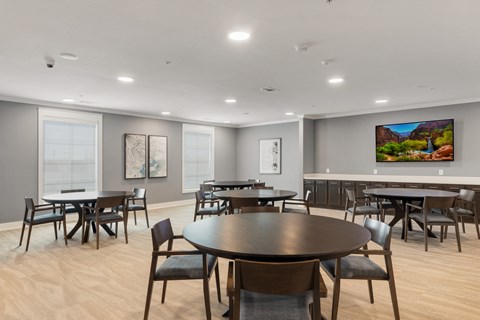 a communal clubhouse dining room with tables and chairs at a senior apartment community