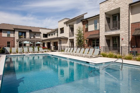 a resort-style pool with lounge chairs at a senior apartment community