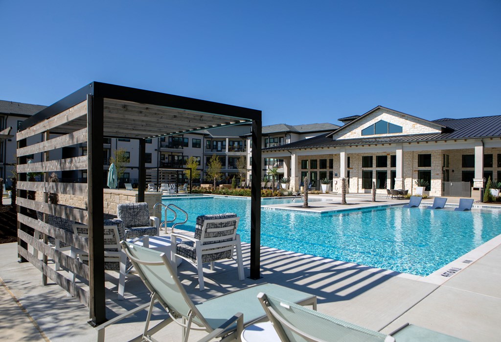 a swimming pool with chairs and a building in the background
