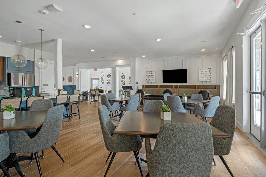 a communal clubhouse dining room with tables and chairs at a senior apartment community