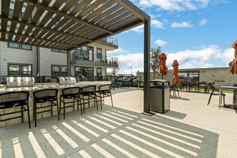 a patio with tables and chairs and a pergola at a senior apartment community