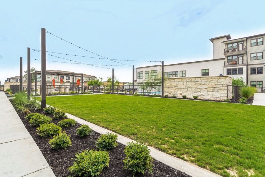 a yard with grass and a fence with buildings in the background