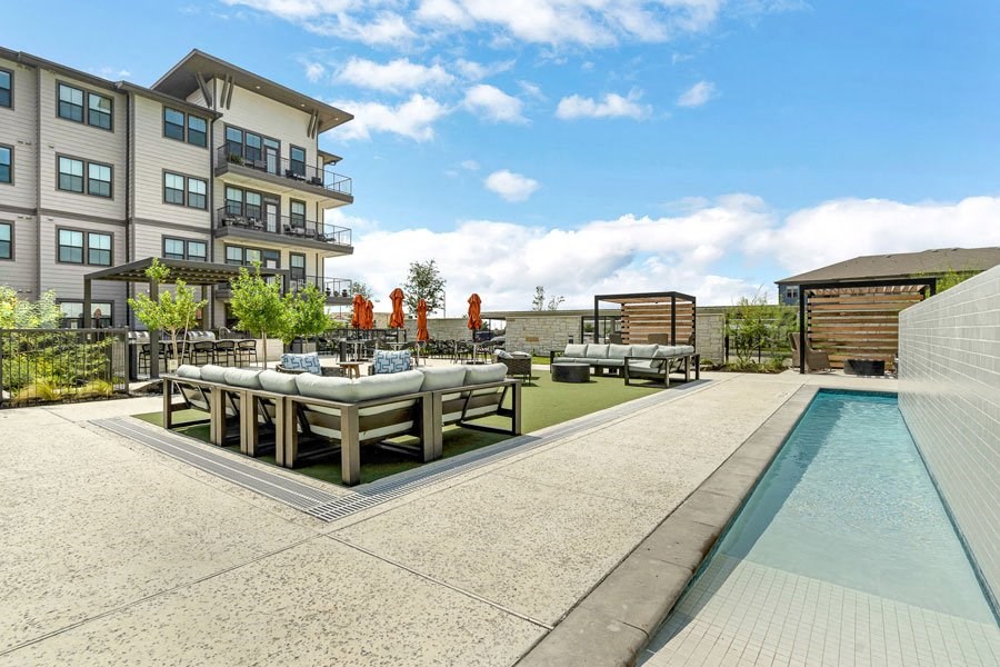 an outdoor dining area with tables and chairs next to a resort-style pool at a senior apartemtn community