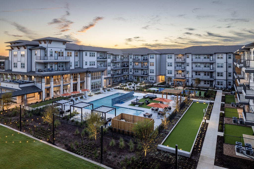 an aerial view of an apartment complex with a pool at dusk