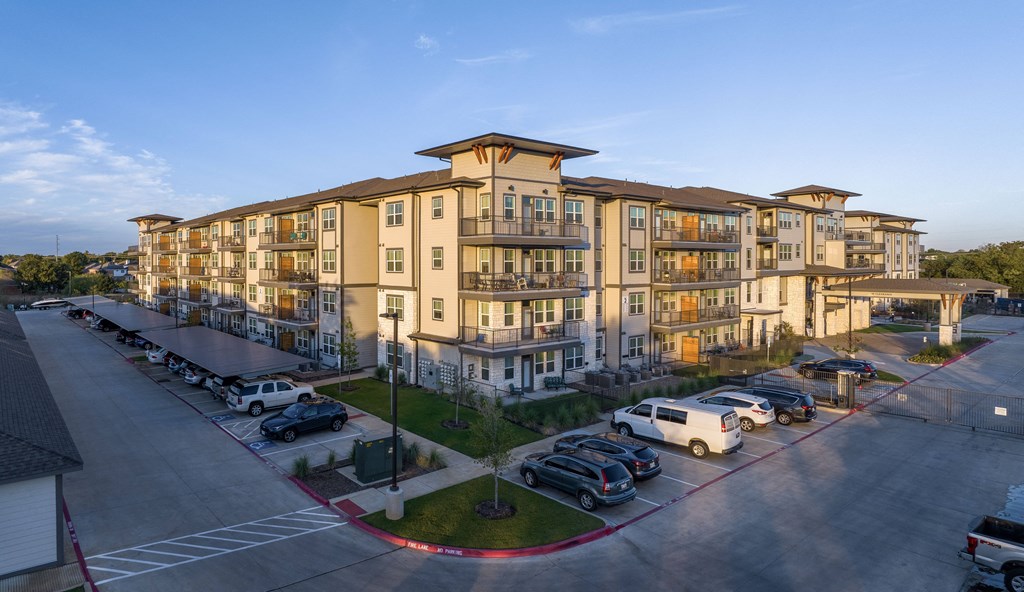 an aerial view of an apartment building with cars parked in front of it