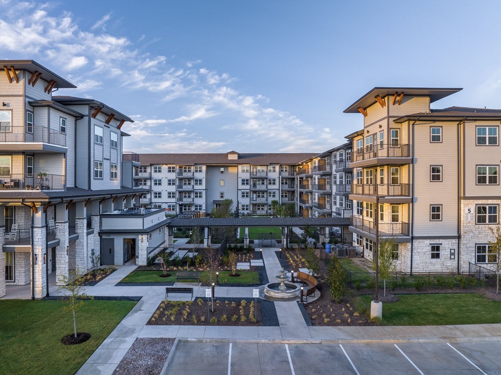an aerial view of an apartment complex with a courtyard and a bridge