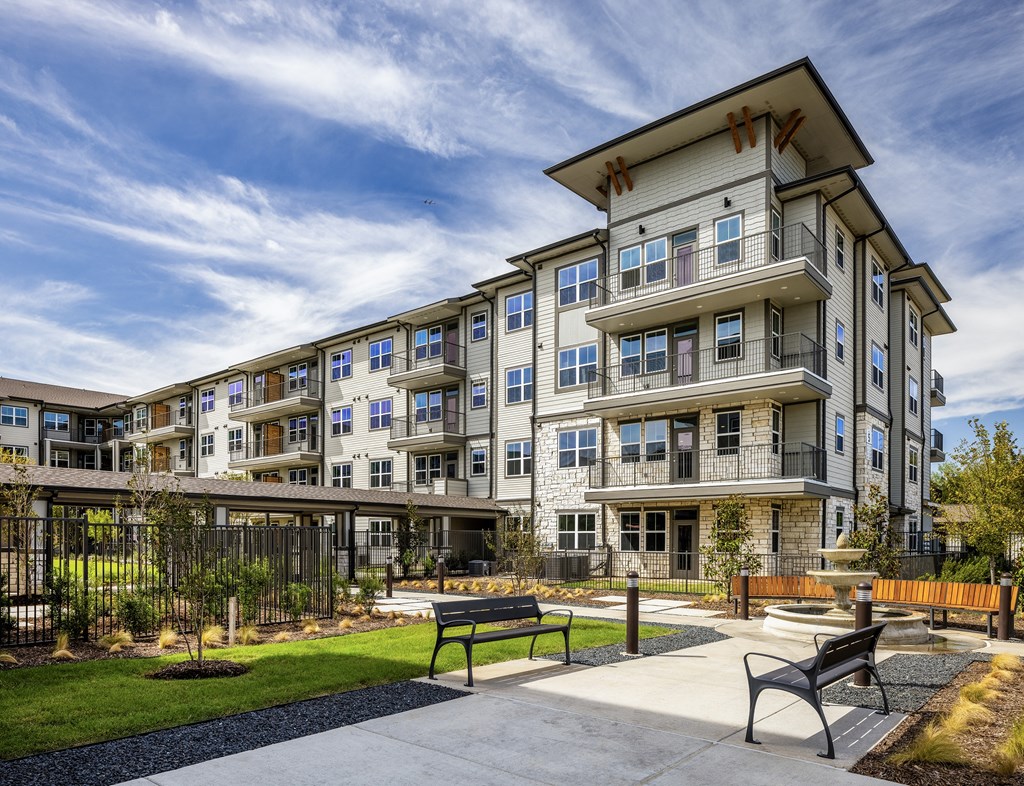 an apartment building with a courtyard with benches and a fire pit