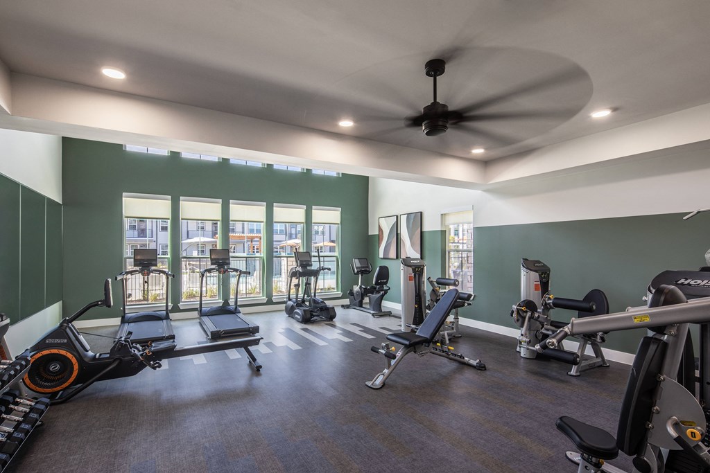 a gym with treadmills and other exercise equipment and a ceiling fan