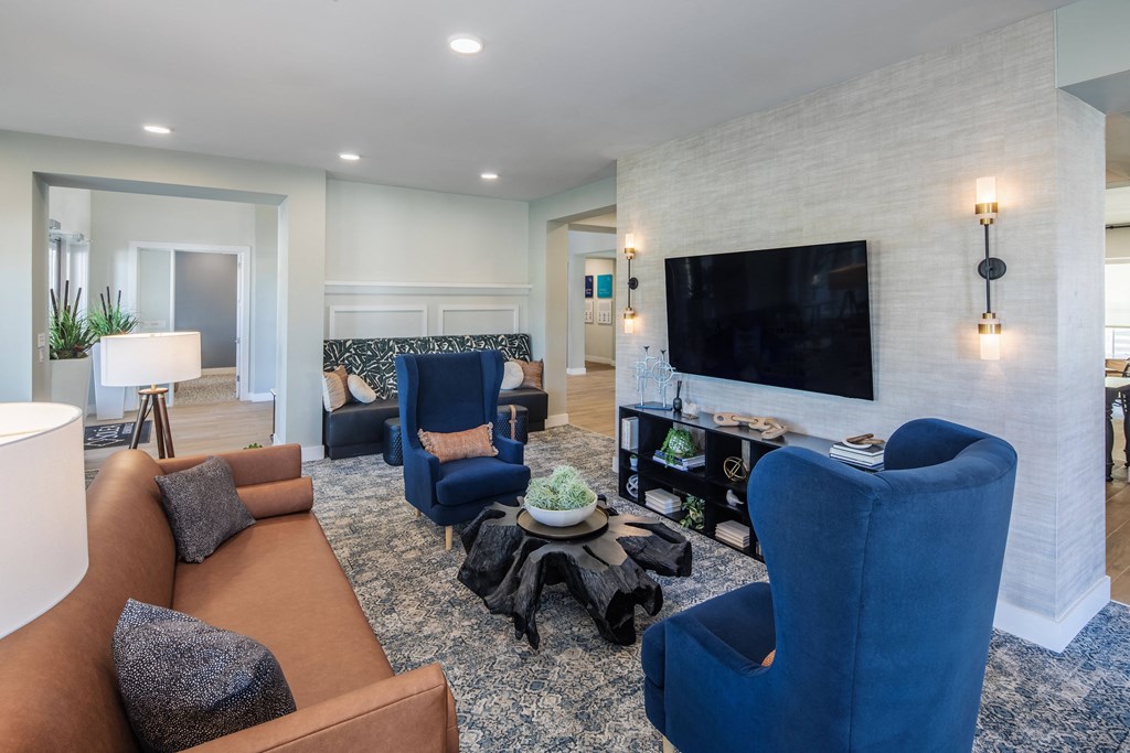 a living room with blue chairs and a tv