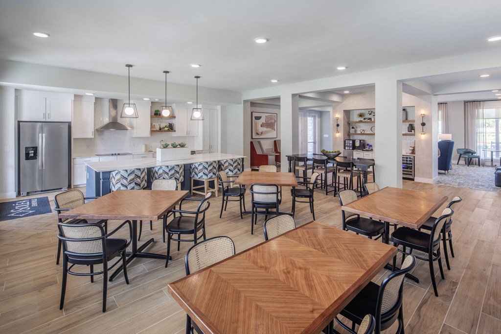 a communal dining area with tables and chairs and a kitchen with a counter and appliances