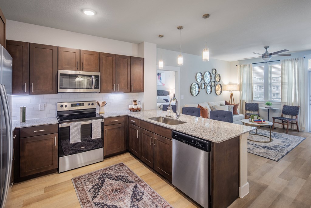 an open kitchen and living room with a large island and stainless steel appliances