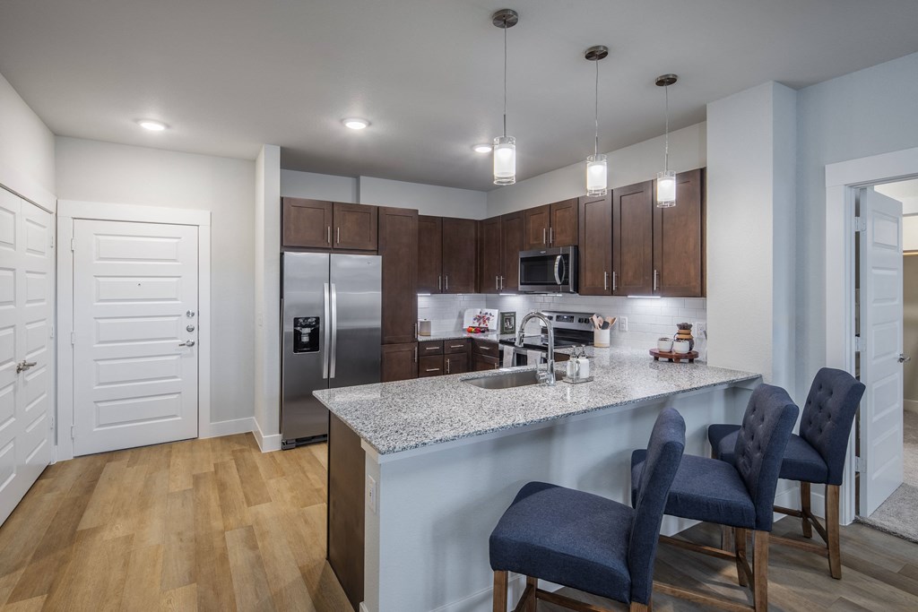a kitchen with a marble counter top and a stainless steel refrigerator