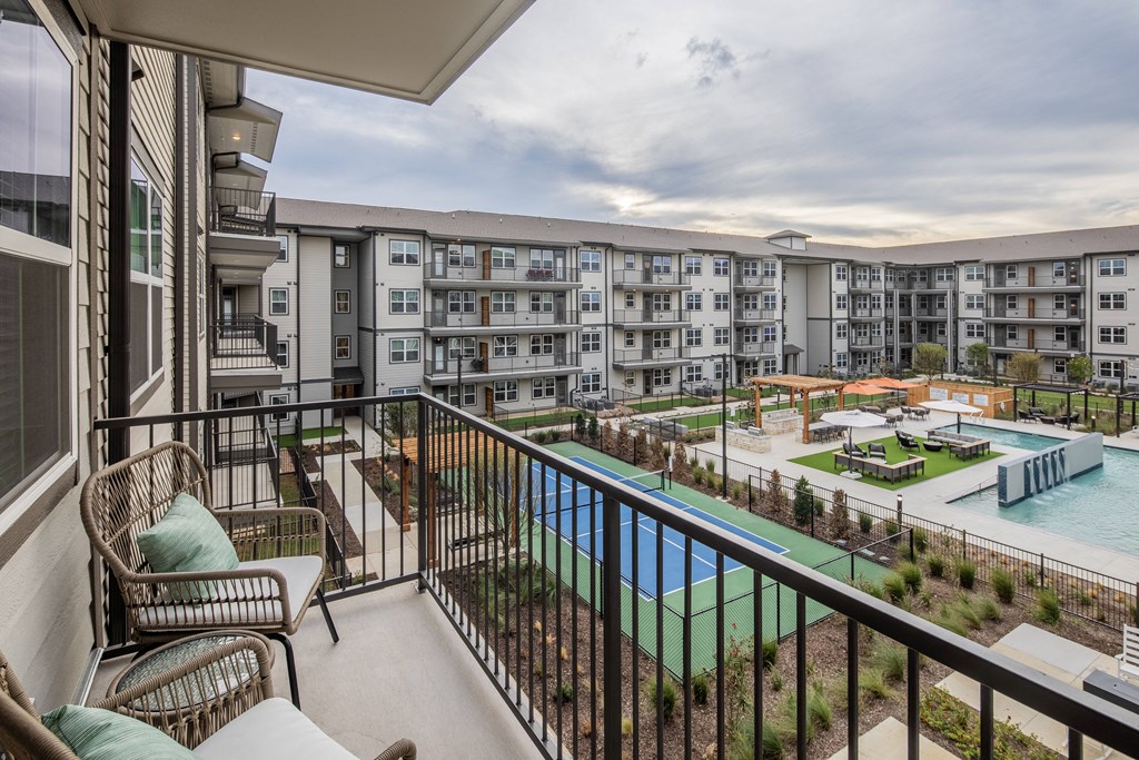 a balcony with a pool and apartments in the background