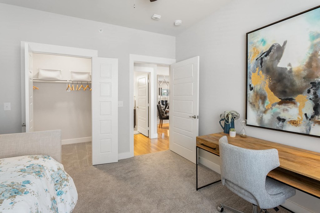 a bedroom with a daybed, desk, and small walk-in closet at a senior apartment community