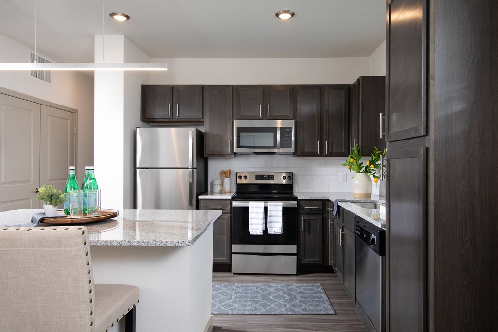 a kitchen with stainless steel appliances, granite countertops and an island at a senior apartment community