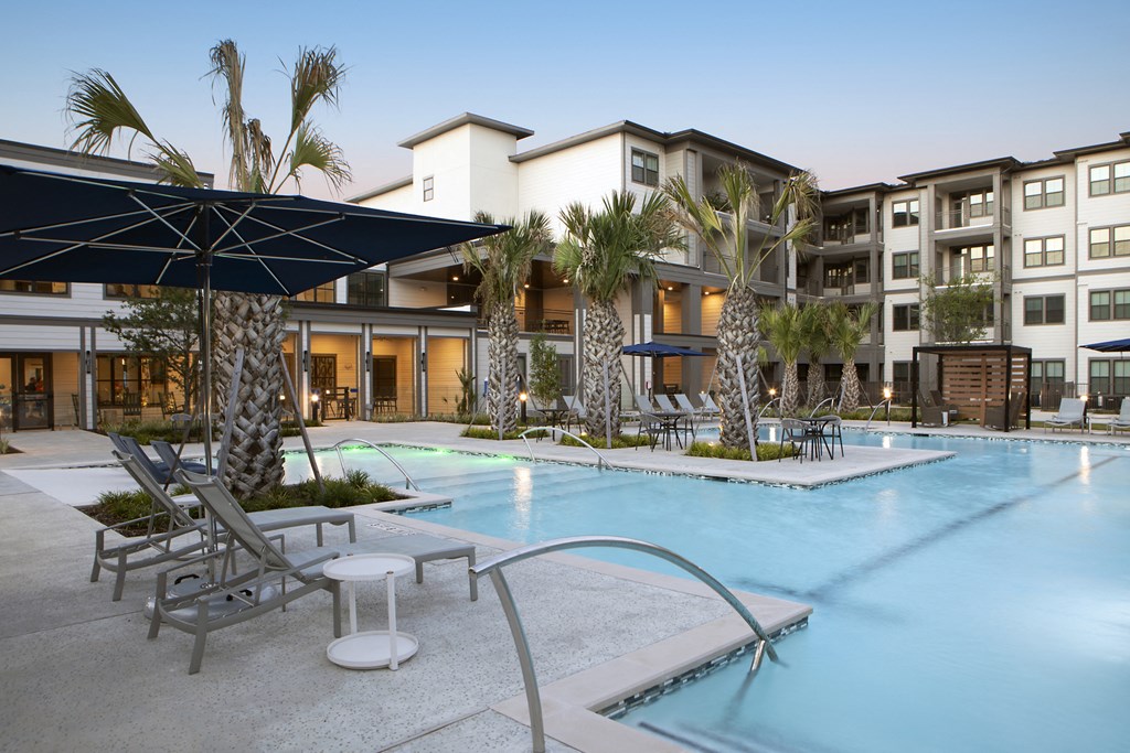 a resort-style pool with railing and lounge chairs at a senior apartment community
