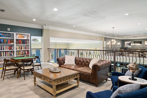 A living room with a brown couch, a coffee table, and a bookshelf filled with books.