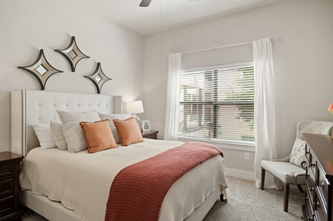 A bedroom with a large bed and a window with blinds.