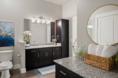 A bathroom with a toilet, sink, and mirror.