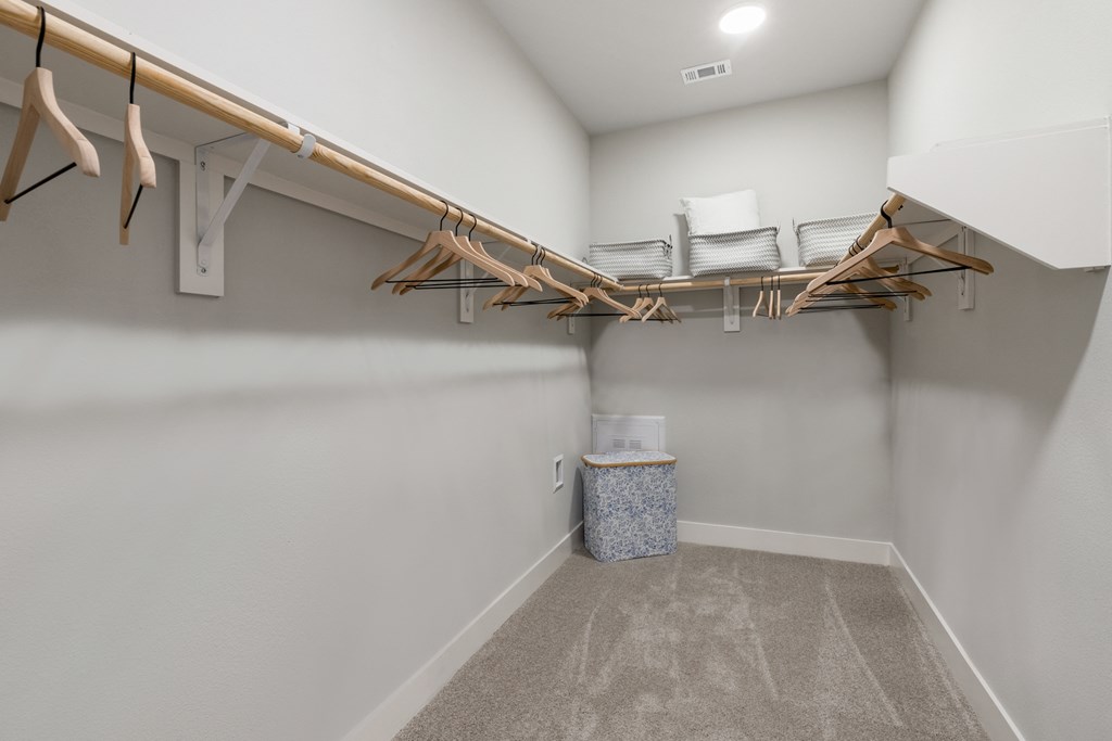 our spacious walk in closet with a large rack of clothes and a basket of laundry