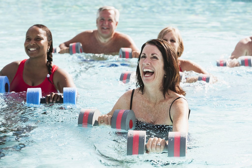 a group of people exercising in a swimming pool with dumbbells