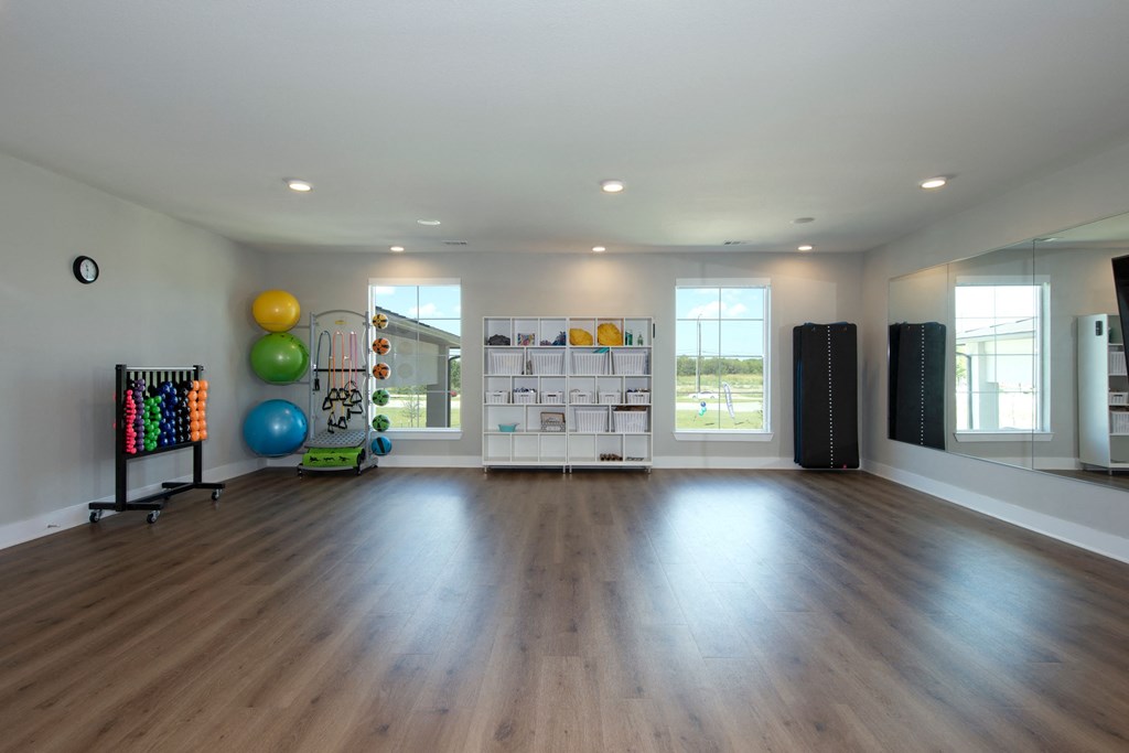 a large room with hardwood flooring and a large window and a workout room