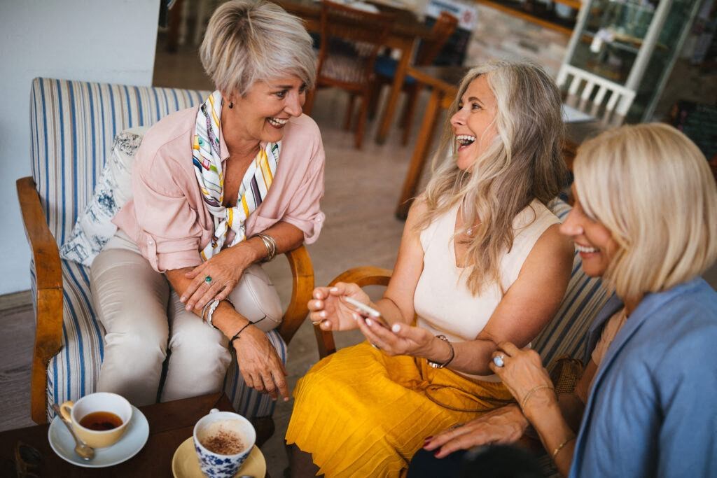 three women sitting and laughing together at a senior apartment community