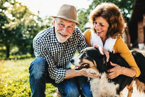 a man and woman petting a dog outside at a senior apartment community
