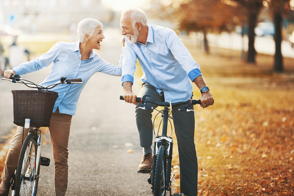 an older man and woman riding bikes and laughing