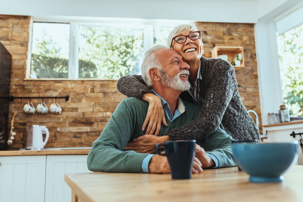 an older man and woman laughing in a kitchen