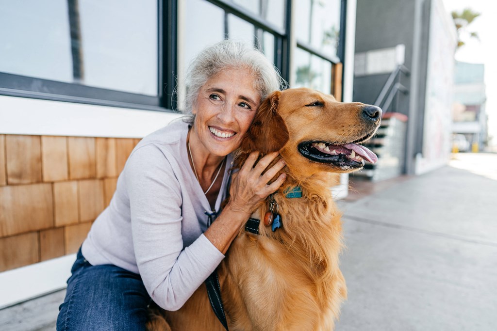 an older woman sitting with her dog in front of a building