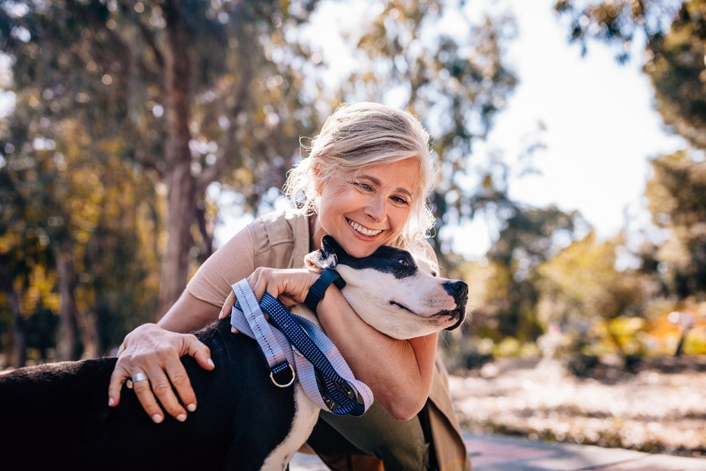 a woman hugging a dog outside at a senior apartment community