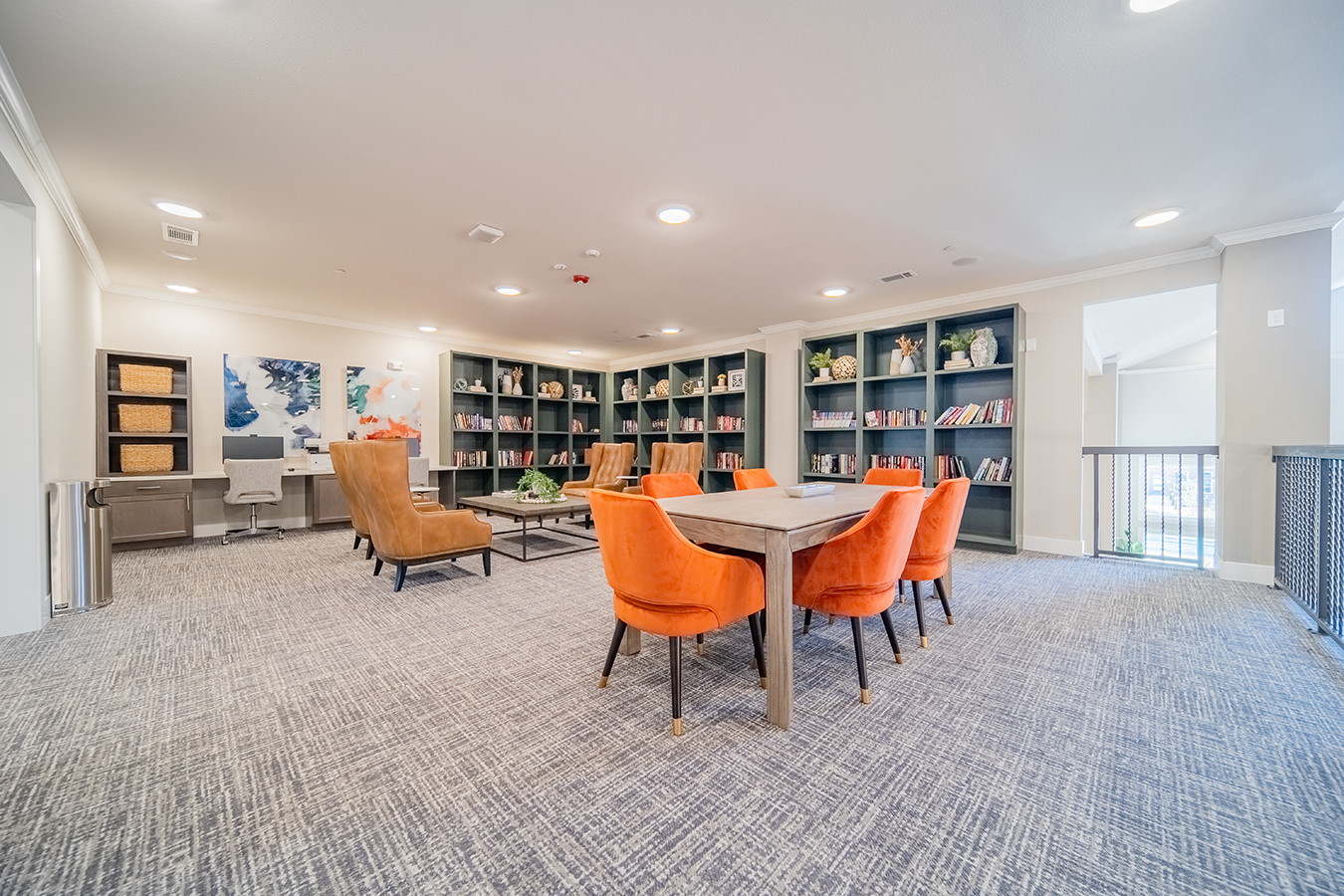 a community room with a table and chairs and a library