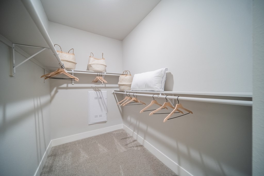 a walk in closet with a white wall and a shelf with bags and hangers