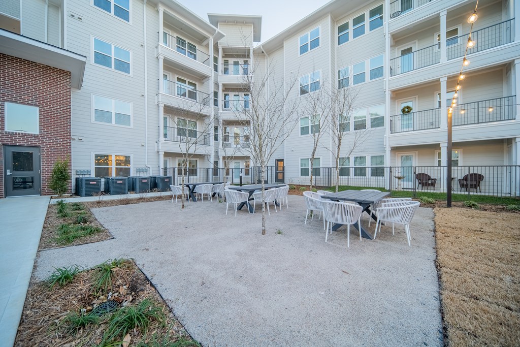 an empty courtyard with tables and chairs in front of an apartment building